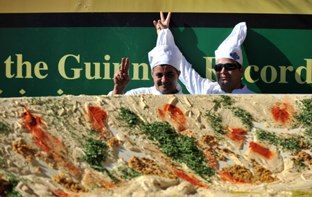 Two chefs pose for photos beside the world's biggest hummus in Abu Gosh, an Arab village about 10 kilometers west of Jerusalem, on January 8, 2010.