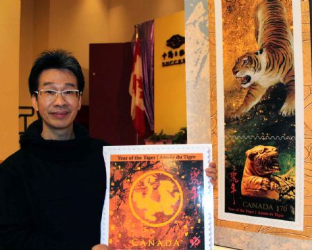 Canadian Chinese Wilson Lam poses for photos with a sample of the tiger stamp designed by him during a reception to celebrate Canada Post's issuing a set of Year of the Tiger stamps to mark the upcoming Chinese lunar new year in Ottawa, Canada, January 8, 2010.