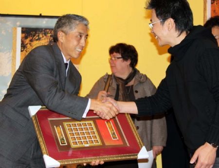 Representative of the Canadian post service presents a tiger stamp to its designer Canadian Chinese Wilson Lam during a reception to celebrate Canada Post's issuing a set of Year of the Tiger stamps to mark the upcoming Chinese lunar new year in Ottawa, Canada, January 8, 2010.