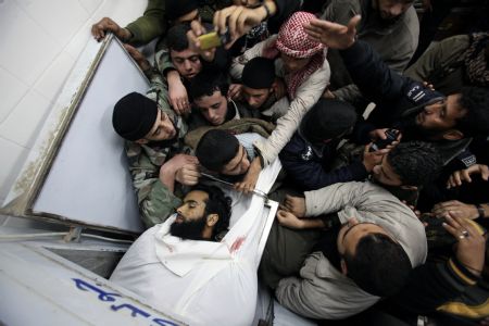 Palestinians mourn over the body of a Gaza militant killed in an Israeli missile strike, in the central Gaza town of Deir al-Balah, January 10, 2010.