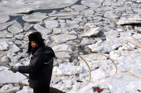 A mariculturist breaks the ice on the sea in Jiaozhou, east China's Shandong Province, January 10, 2010.