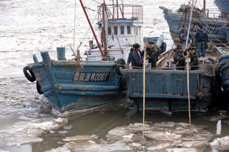 Police help move the vessels stucked by ice in Qingdao, east China's Shandong Province, January 10, 2010. 