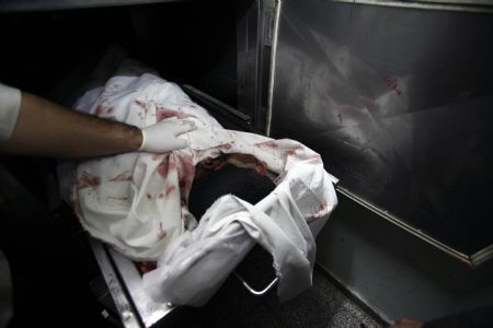 Palestinians look at the body of a militant after he was killed in an Israeli air strike in Beit Hanoun, northern Gaza Strip January 11, 2010. 