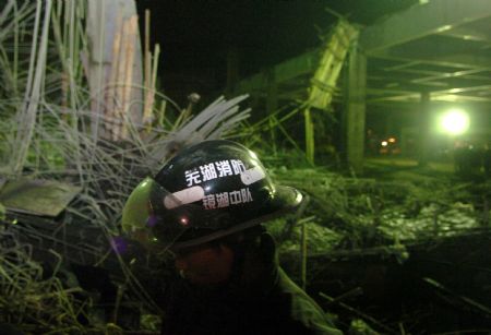 A rescuer works at the scene of a collapse accident at the construction site of Wuhu Huaqiang Culture and Technology Park in Wuhu, east China's Anhui Province, January 12, 2010.