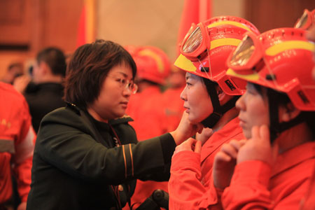 A female armed police official helps fastening helmet of a female member of a Chinese rescue team before the 50-member team's departure for quake-hit Haiti, at the Capital International Airport in Beijing, capital of China, January 13, 2010. 