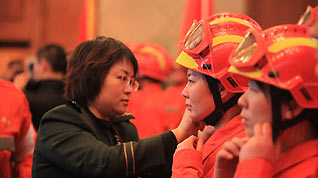 A female armed police official helps fastening helmet of a female member of a Chinese rescue team before the 50-member team's departure for quake-hit Haiti, at the Capital International Airport in Beijing, capital of China, January 13, 2010.