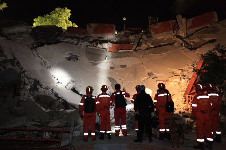 Members of a Chinese emergency rescue team inspect the collapsed building of the headquarters of the UN Stabilization Mission in Port-au-Prince, Haiti, Jan. 14, 2010. The Chinese emergency rescue team arrived in Haiti's capital Port-au-Prince early Thursday local time, to help the rescue operation after an earthquake in which up to 100,000 people are feared dead and eight Chinese are still missing. (Xinhua/Xing Guangli)