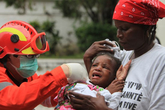 A Chinese rescuer gives medical treatment to an injured Haitian kid in Port-au-Prince on Thursday, January 14, 2010.