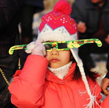 A small girl uses solar viewer to view an annular solar eclipse in Qingdao of east China&apos;s Shandong Province, Jan. 15, 2010. 