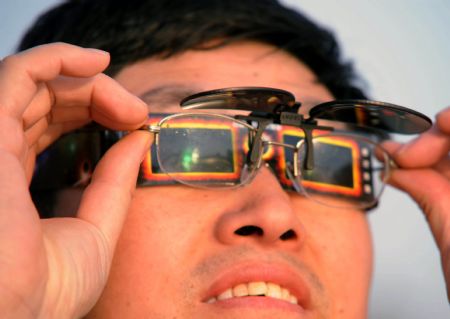 A man wears solar viewer to view an annular solar eclipse in Qingdao of east China&apos;s Shandong Province, Jan. 15, 2010. 