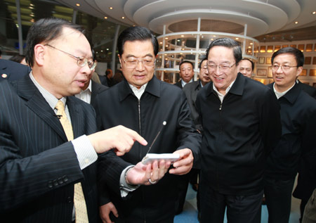 Hu Jintao (2nd L, front), general secretary of the Central Committee of the Communist Party of China, Chinese president and chairman of the Central Military Commission, tries the TV and video communication functions of a mobile phone as he inspects Spreadtrum Communications, Inc., in Shanghai, east China, on January 16, 2010.