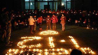 Students of the Xiang'e Primary School pray as they hold candles for Haiti children who are suffering from earthquake in Dujiangyan, southwest China's Sichuan Province, which was hit by strong earthquake last May, on January 18, 2010.