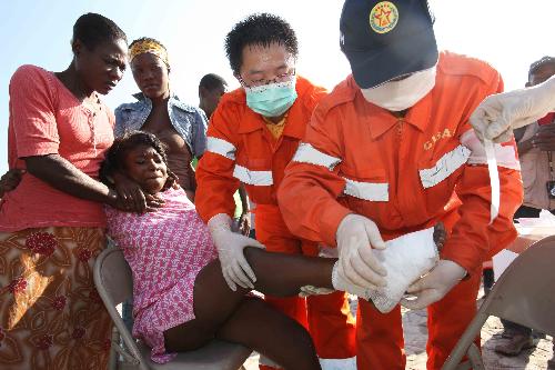 Medical workers of China International Search and Rescue Team (CISAR) bind up the wounded foot for a girl in Port-au-Prince, Haiti, January 18, 2010. 