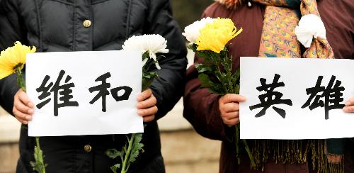 Mourners holding banners wait for the arrival of the coffins of the eight peacekeeping police officers who were killed in the Haiti earthquake at the Babaoshan Revolutionary Cemetery in Beijing January 19, 2010. 