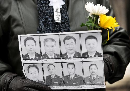 A mourner holding the portraits of eight peacekeeping police officers who were killed in the Haiti earthquake waits for the arrival of their coffins at the Babaoshan Revolutionary Cemetery in Beijing, January 19, 2010. 