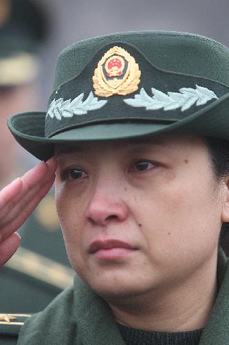 A policewoman bids farewell to the coffins of the eight peacekeeping police officers who were killed in the Haiti earthquake at the Chang'an Street in Beijing, China, January 19, 2010.