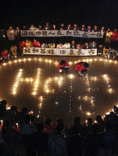 Teachers and students of No.1 Middle School in Hanshan county, east China's Anhui Province, light candles to commemorate THE eight Chinese peacekeepers died in the earth quake of Haiti and pray for the Haitians, January 18, 2010.