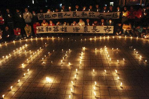 Teachers and students of No.1 Middle School in Hanshan county, east China's Anhui Province, light candles to commemorate the eight Chinese peacekeepers died in the earth quake of Haiti and pray for the Haitians, January 18, 2010.