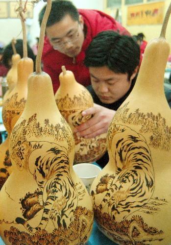 Local craftsmen make pyrograph of Tiger pattern on cucurbits for the approaching Year of Tiger according to Chinese lunar calendar at Luzhuang Village of Liaocheng, east China's Shandong Province, January 19, 2010.