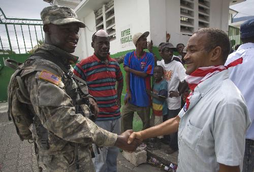 A US soldier (L) shakes hands with a local citizen in Port-au-Prince, Haiti, January 18, 2010. 