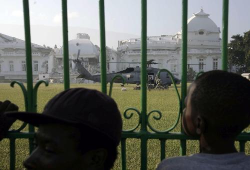 Local people look at a US army's helicopters at the harbor in Port-au-Prince, Haiti, January 18, 2010.