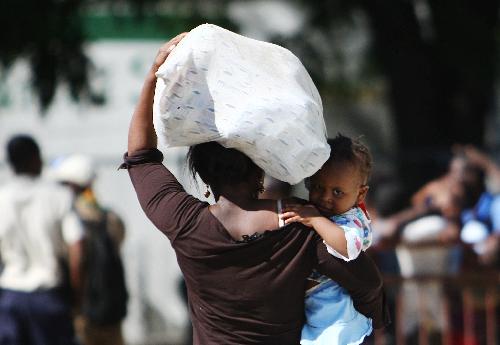 A Haitian woman carries just-received aid supplies in Port-au-Prince, Haiti, January 20, 2010.
