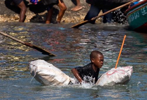 A kids tries to reach a boat to flee this destroyed city by boat in Port-au-Prince, Haiti, January 20, 2010.