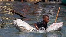 A kids tries to reach a boat to flee this destroyed city by boat in Port-au-Prince, Haiti, January 20, 2010.