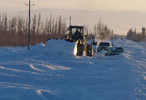 A snow removing machine clears snow along a road in Tacheng, northwest China's Xinjiang Uygur Autonomous Region, Jan. 20, 2010.