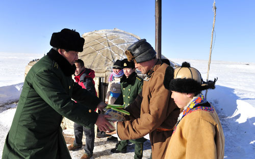 A border policeman distributes relief goods to herdsmen in Xilingol, north China's Inner Mongolia Autonomous Region, January 20, 2010.