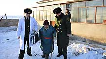 Medical officers from a Chinese border police station offers a woman help after giving her a health checkup in Xilingol, north China's Inner Mongolia Autonomous Region, January 21, 2010.