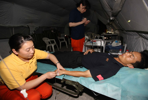 Cai Yukun (L), a member of Chinese formed police unit in Haiti, receives medical treatment after he collapses because of overwork in Port-au-Prince, Haiti, January 19, 2010.