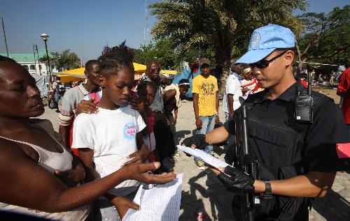 Tang Jun, a member of Chinese formed police unit in Haiti, hands over booklets about epidemic prevention in Port-au-Prince, Haiti, January 19, 2010.
