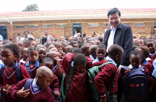 Chinese Consul General to Johannesburg Fang Li stands with children who have received schoolbags donated from overseas Chinese in Diepkloop, Soweto, Johannesburg, South Africa, January 22, 2010. 