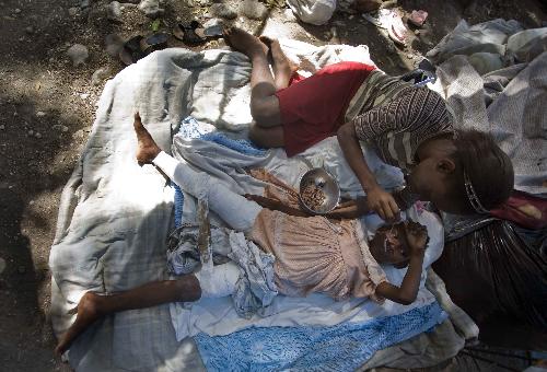 A mother feeds her injured daughter at a makeshift shelter in Port-au-Prince, Haiti, January 22, 2010. A 7.3 magnitude earthquake hit the country on January 12, 2010.