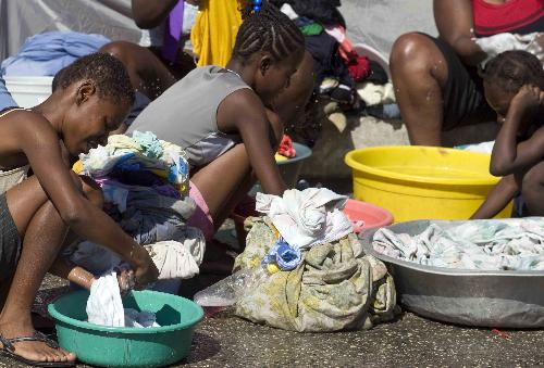 Children wash clothes at a makeshift shelter in Port-au-Prince, Haiti, January 22, 2010. A 7.0 magnitude earthquake hit the country on January 12, 2010.