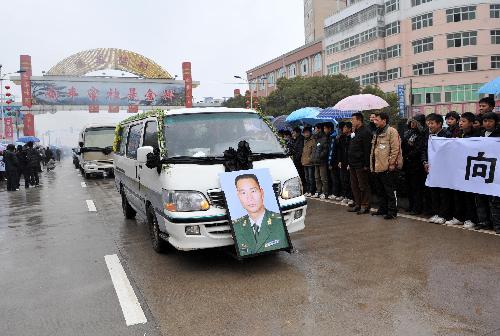 Local people hold banners to bid farewell to Zhong Jianqin, a Chinese peacekeeping police officer who were killed in the 7.3-magnitude earthquake in Haiti, as a vehicle carrying his bone ash passes by in Nanfeng county of east China's Jiangxi Province, January 23, 2010.