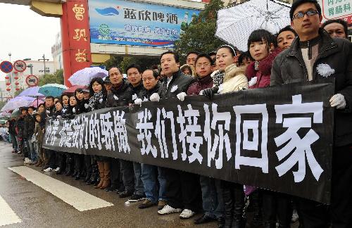 Local people hold banners to bid farewell to Zhong Jianqin, a Chinese peacekeeping police officer who were killed in the 7.3-magnitude earthquake in Haiti, in Nanfeng county of east China's Jiangxi Province, January 23, 2010.