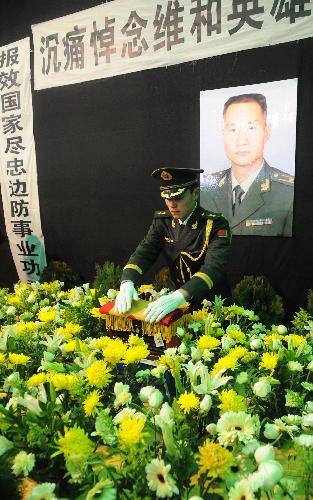An armed policeman place the bone ash of Zhong Jianqin, a Chinese peacekeeping police officer who were killed in the 7.3-magnitude earthquake in Haiti, after it was returned to his home town in Nanfeng county of east China's Jiangxi Province, January 23, 2010.