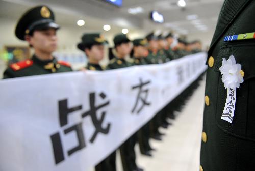 Border defence soldiers hold banners to bid farewell to Zhong Jianqin, a Chinese peacekeeping police officer who were killed in the 7.3-magnitude earthquake in Haiti, at the Changbei airport in Nanchang, capital of east China's Jiangxi Province, January 23, 2010.