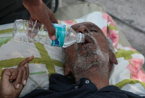 An injured Haitian drinks water in a temporary hospital in Port-au-Prince, Haiti, January 23, 2010.