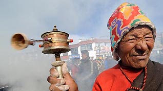 An elderly Buddhist believer holds a prayer wheel during the replacement ceremony of prayer streamers around the Jokhang Temple in Lhasa, capital of southwest China's Tibet Autonomous Region, January 26, 2010.