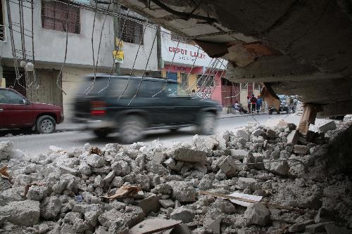 A vehicle drives past ruins of destroyed buildings in Haitian capital Port-au-Prince on January 25, 2010. Life for locals began to recover from the chaos caused by a catastrophic earthquake that rocked the city on January 12.