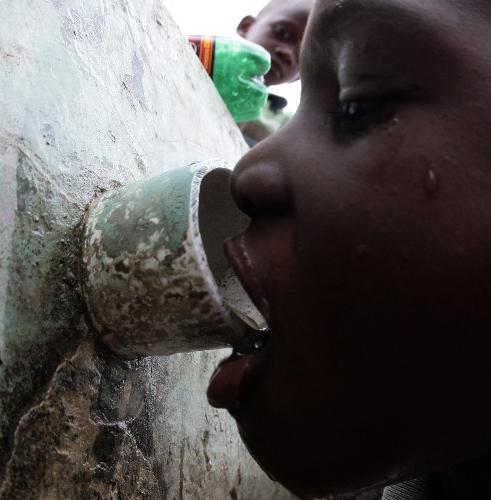 A Haitian child drinks from a water pipe in Haitian capital Port-au-Prince on January 25, 2010. Life for locals began to recover from the chaos caused by a catastrophic earthquake that rocked the city on January 12.
