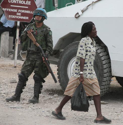 A woman walks past a UN peacekeeper in Haitian capital Port-au-Prince on January 25, 2010. Life for locals began to recover from the chaos caused by a catastrophic earthquake that rocked the city on January 12.
