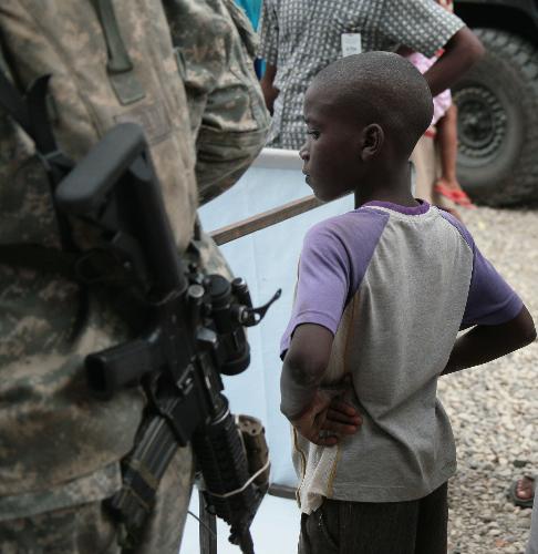 A child stands beside a UN peacekeeper in Haitian capital Port-au-Prince on January 25, 2010. Life for locals began to recover from the chaos caused by a catastrophic earthquake that rocked the city on January 12.