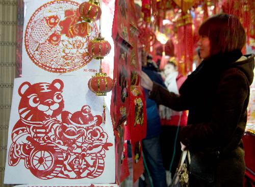 A woman chooses paper-cuts with tiger figures at a market in Urumqi, capital of northwest China's Xinjiang Uygur Autonomous Region, January 26, 2010. 