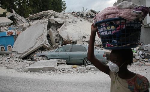 A woman walks past a destroyed building in Haitian capital Port-au-Prince on January 25, 2010. 
