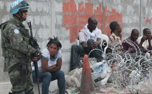 A UN peacekeeper stands beside a few Haitians in Haitian capital Port-au-Prince on January 25, 2010.