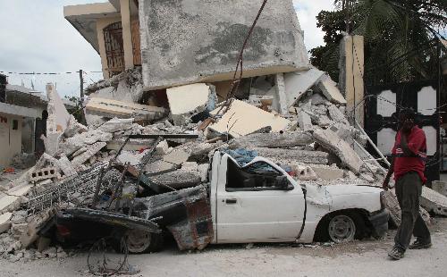 A man walks past a destroyed car in Haitian capital Port-au-Prince on January 25, 2010. 